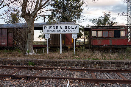 Cartel de la estacióm de tren Piedra Sola Empalme con Línea Salto con el fondo de vagones antiguos - Departamento de Paysandú - URUGUAY. Foto No. 74027