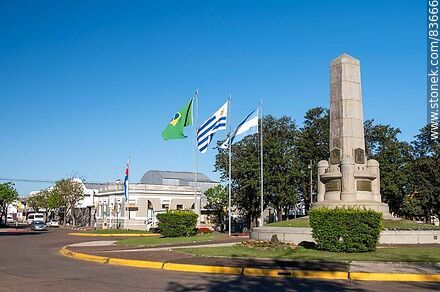 Obelisco y banderas locales e internacionales en la plaza Batlle y Ordóñez - Departamento de Artigas - URUGUAY. Foto No. 83666